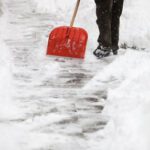 Man shoveling snow from the sidewalk in front of his house after